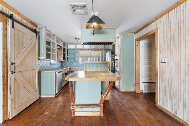 kitchen with appliances with stainless steel finishes, stainless steel countertops, visible vents, and a barn door