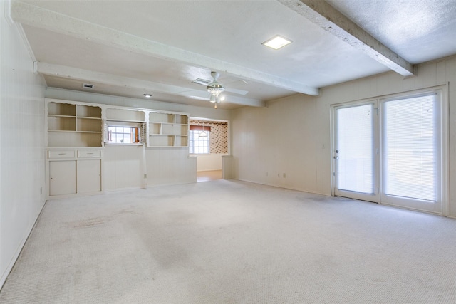 empty room with a ceiling fan, light colored carpet, beamed ceiling, and a textured ceiling