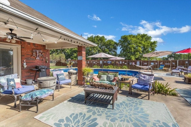 view of patio with an outdoor hangout area, a fenced backyard, a community pool, and a ceiling fan