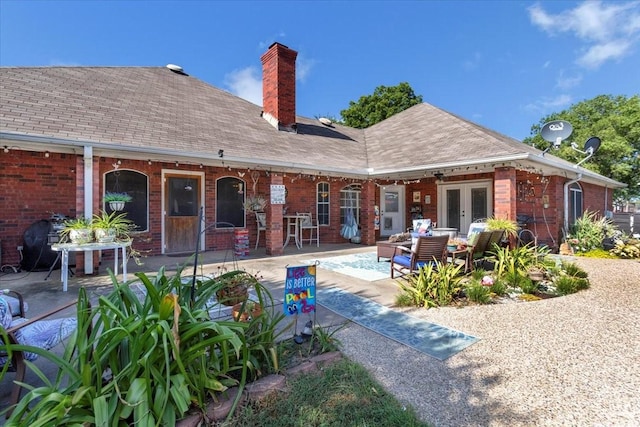 back of property with french doors, brick siding, a chimney, and a patio area