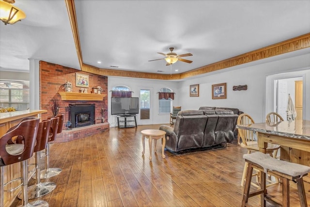 living room featuring a brick fireplace, ceiling fan, and hardwood / wood-style floors