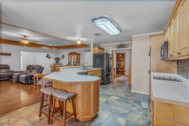 kitchen featuring a peninsula, a sink, visible vents, black appliances, and a kitchen bar