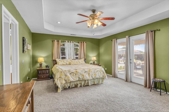 bedroom featuring visible vents, a raised ceiling, a ceiling fan, access to outside, and carpet flooring