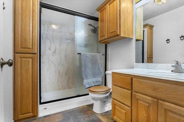 full bath with vanity, a marble finish shower, toilet, and stone finish flooring