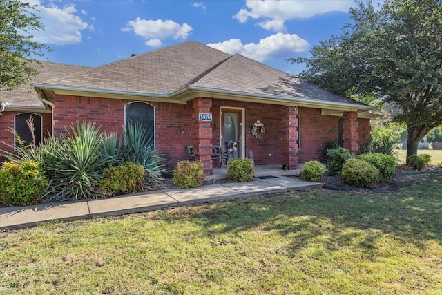 single story home with brick siding, a front yard, and a shingled roof