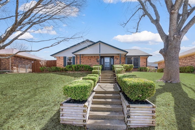 view of front facade featuring stairs, brick siding, a front yard, and fence