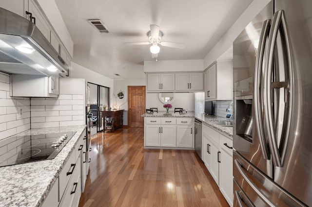 kitchen with light wood-style flooring, under cabinet range hood, a ceiling fan, white cabinets, and appliances with stainless steel finishes