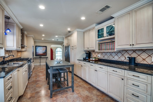 kitchen featuring tasteful backsplash, arched walkways, visible vents, and a sink