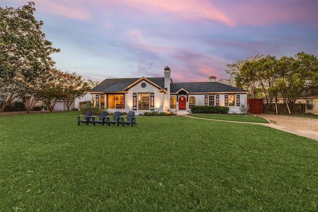 back of property with a lawn, a chimney, and fence