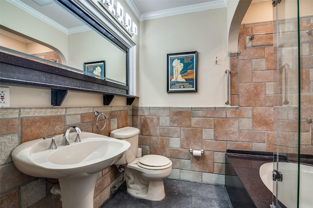 full bath featuring enclosed tub / shower combo, wainscoting, crown molding, toilet, and tile walls