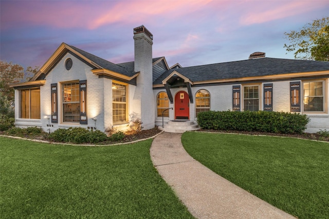 view of front of property with brick siding, a chimney, and a front lawn