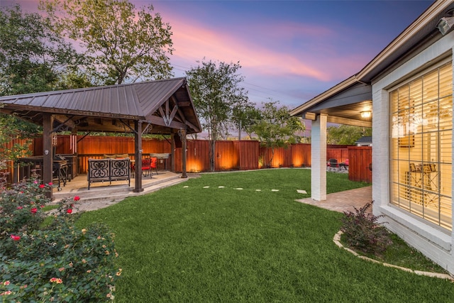 yard at dusk with a gazebo, a patio area, and a fenced backyard