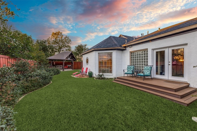 yard at dusk with a gazebo, fence, and french doors