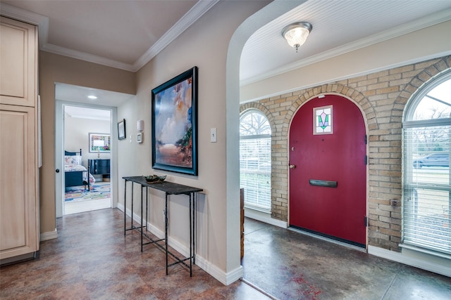 entrance foyer featuring baseboards, arched walkways, concrete floors, and ornamental molding