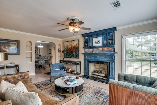 living area with visible vents, arched walkways, wood finished floors, and crown molding