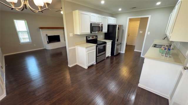 kitchen featuring a sink, open floor plan, appliances with stainless steel finishes, light countertops, and dark wood-style flooring