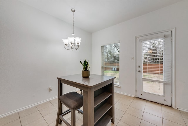 dining area with light tile patterned floors, an inviting chandelier, baseboards, and vaulted ceiling