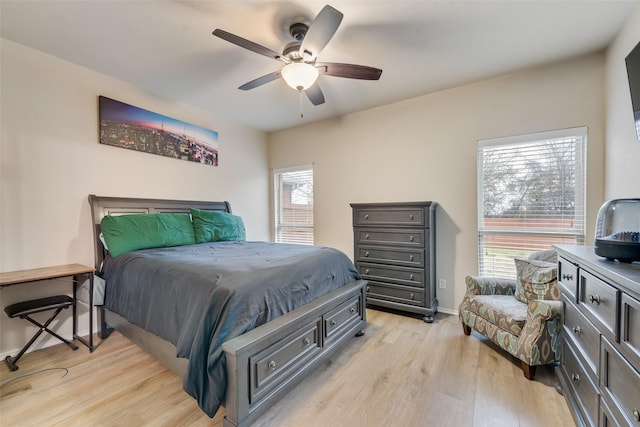 bedroom featuring light wood-style flooring, a ceiling fan, and baseboards