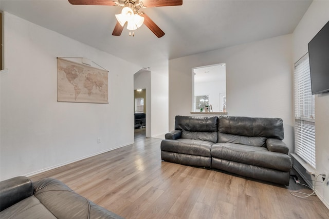 living room featuring ceiling fan, baseboards, and wood finished floors