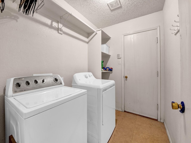 laundry room with visible vents, laundry area, light tile patterned flooring, washer and dryer, and a textured ceiling