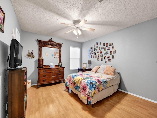 bedroom with light wood-type flooring, baseboards, and a textured ceiling