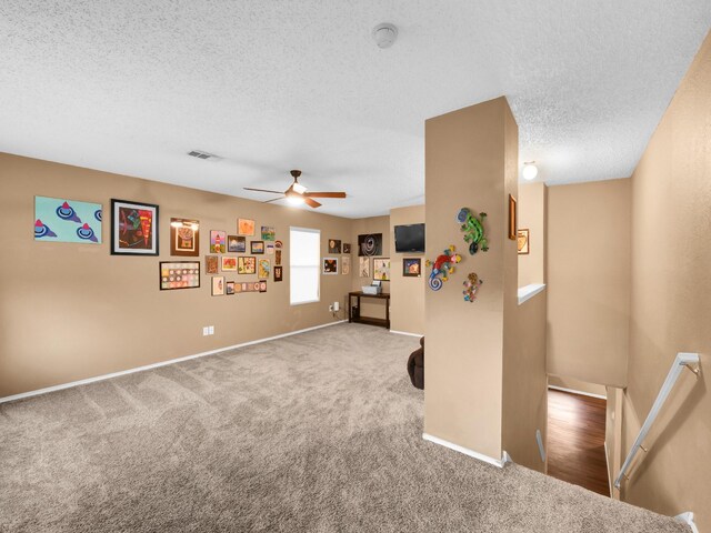 interior space with ceiling fan, visible vents, baseboards, and a textured ceiling