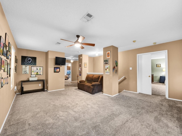 living area featuring carpet, visible vents, baseboards, a textured ceiling, and an upstairs landing