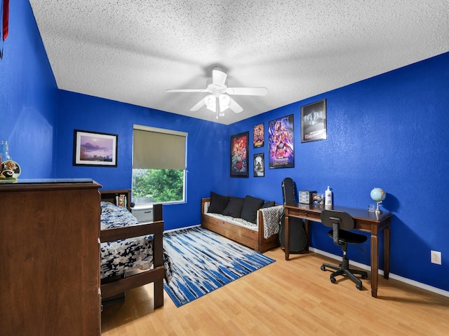 home office with baseboards, ceiling fan, wood finished floors, a textured wall, and a textured ceiling