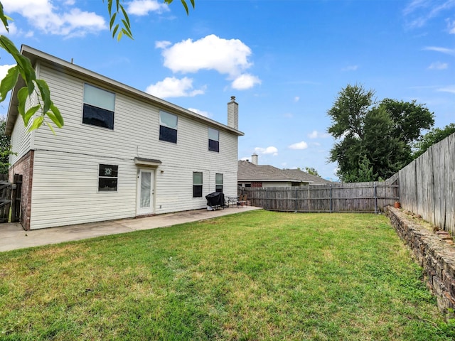 back of house with a fenced backyard, a patio area, a chimney, and a yard