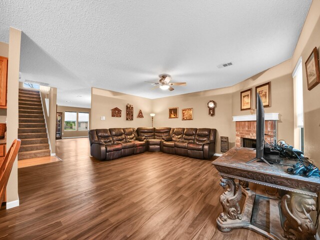 living area featuring visible vents, stairway, a fireplace, wood finished floors, and a textured ceiling