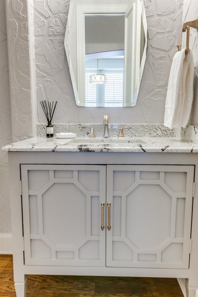 bathroom featuring vanity, wood finished floors, and a textured wall