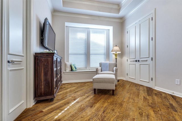 sitting room with baseboards, a raised ceiling, wood finished floors, and crown molding