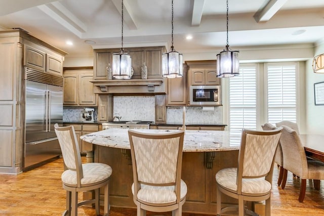 kitchen with decorative backsplash, built in appliances, and light wood finished floors