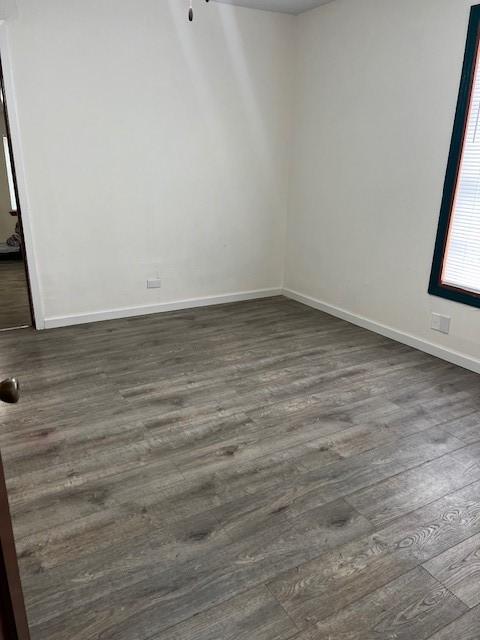 empty room featuring dark wood-style floors and baseboards