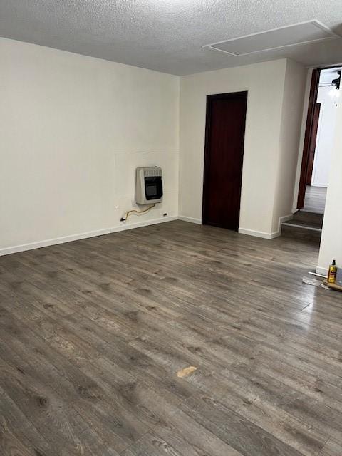 unfurnished room featuring heating unit, a textured ceiling, dark wood-type flooring, and baseboards