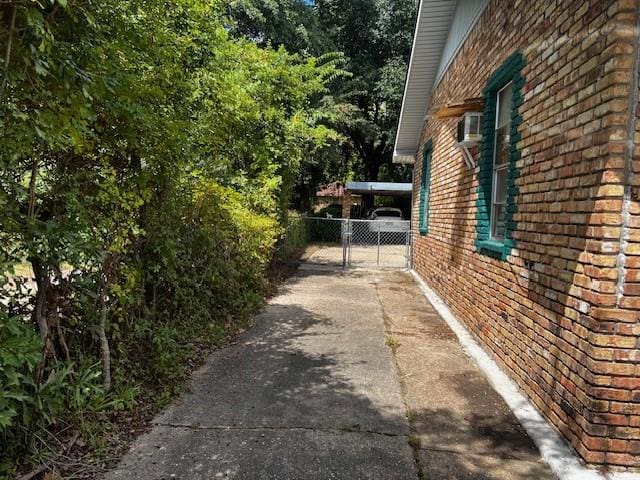 view of side of property with a gate, fence, and brick siding