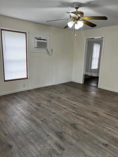 empty room featuring baseboards, dark wood-type flooring, a ceiling fan, and a wall mounted AC