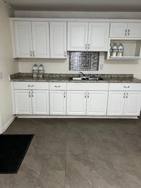 kitchen featuring white cabinetry, open shelves, baseboards, and a sink