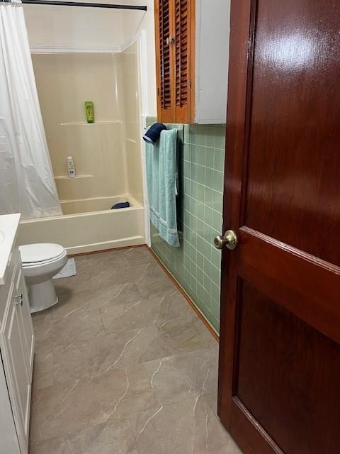 bathroom with toilet, tile walls, vanity, and shower / bathtub combination with curtain