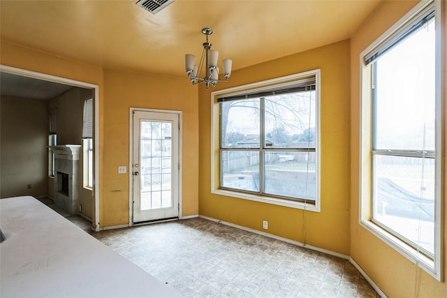 entryway with a notable chandelier, baseboards, visible vents, and a fireplace with flush hearth