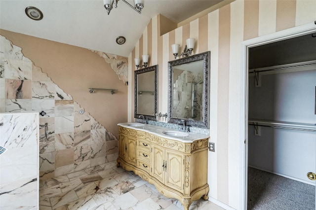 bathroom with a tile shower, marble finish floor, lofted ceiling, and a sink