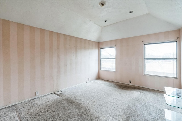 unfurnished room featuring a textured ceiling, carpet, and vaulted ceiling