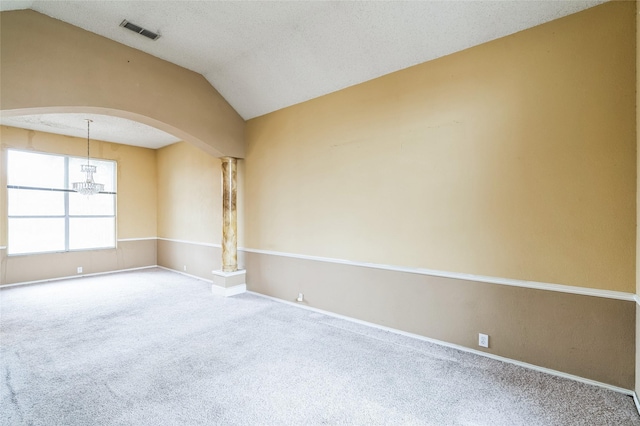 carpeted empty room with visible vents, lofted ceiling, decorative columns, arched walkways, and a textured ceiling