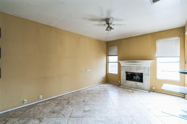 unfurnished living room with baseboards, ceiling fan, and a fireplace