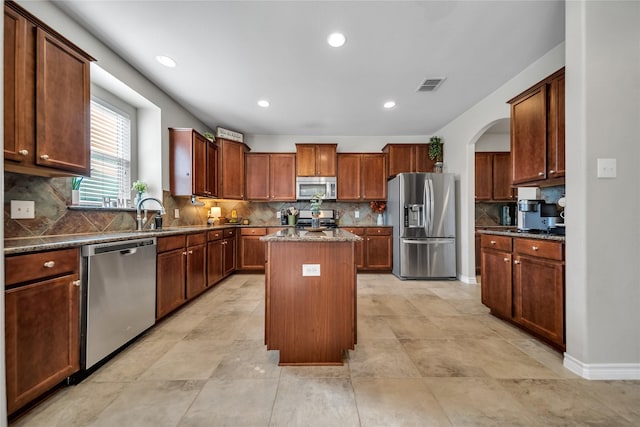 kitchen with visible vents, backsplash, a kitchen island, appliances with stainless steel finishes, and a sink