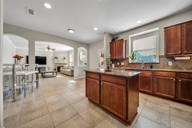 kitchen with decorative backsplash, visible vents, arched walkways, and a kitchen island