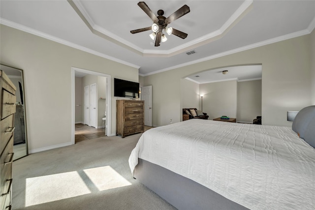 carpeted bedroom with visible vents, a tray ceiling, crown molding, baseboards, and ceiling fan