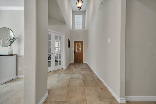 foyer with french doors, baseboards, a high ceiling, and visible vents