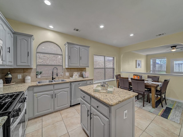 kitchen featuring visible vents, gray cabinetry, a sink, range with gas cooktop, and dishwasher