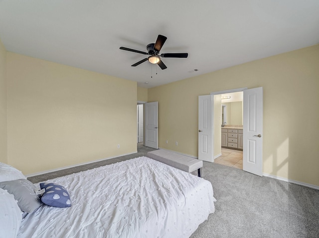 bedroom featuring baseboards, light colored carpet, ensuite bath, and a ceiling fan